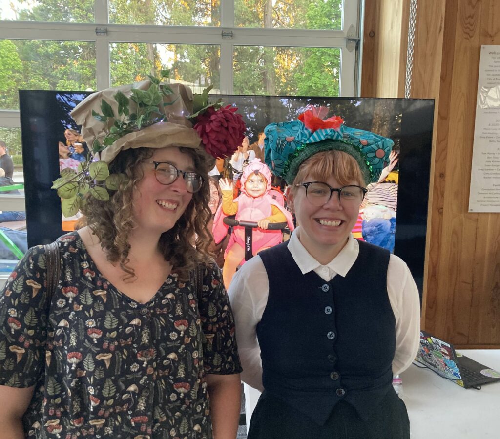 Two people with 2 fine looking just-crafted hats!